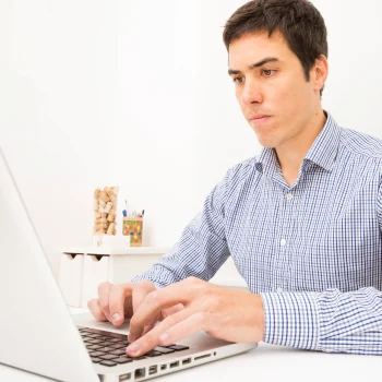 retrato-de-un-joven-empresario-usando-laptop-en-mesa-blanca